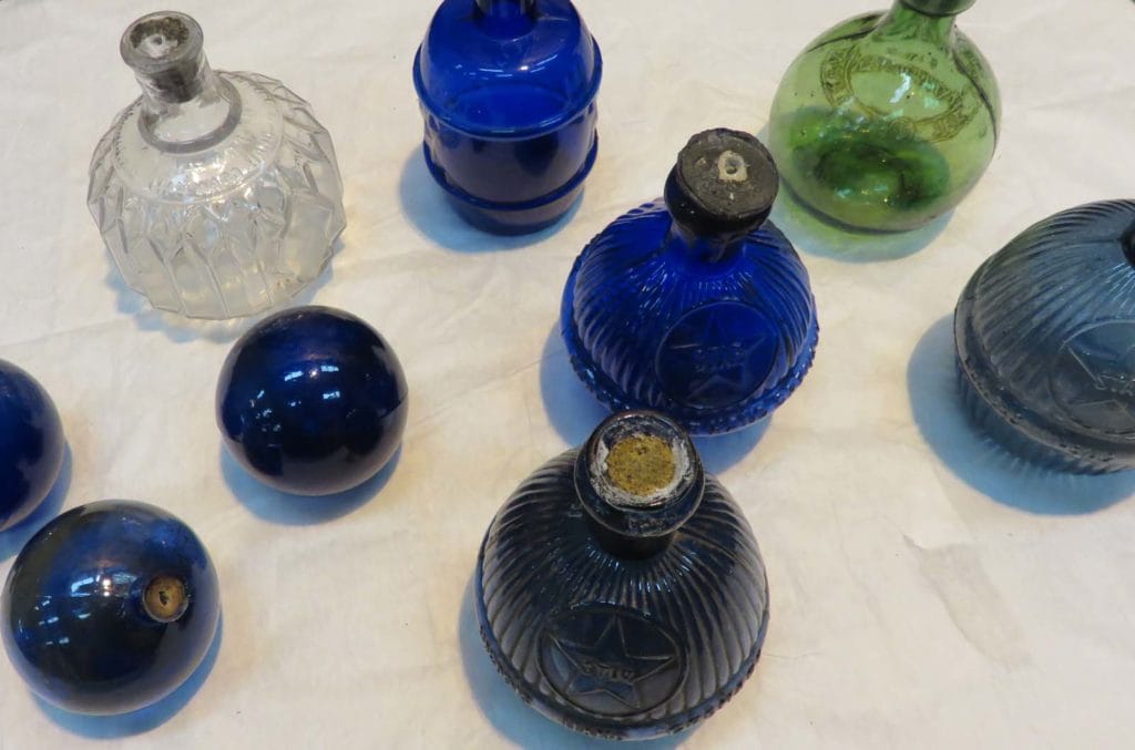 Some blue, green ad clear glass Victorian fire grenades - round glass bottles with long neck.